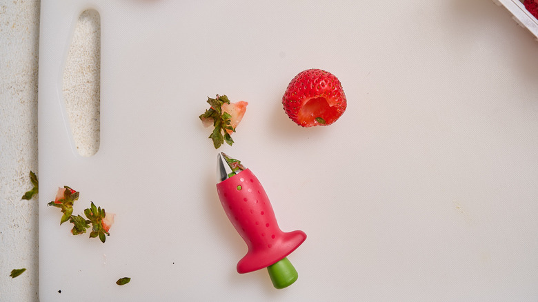 hulling strawberries on cutting board