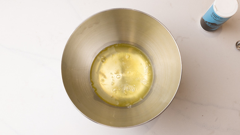 egg whites in a mixing bowl next to container of cream of tartar
