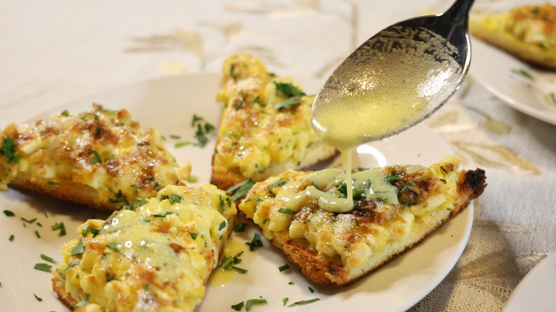 a spoon drizzling vinaigrette onto a plate of egg toasts
