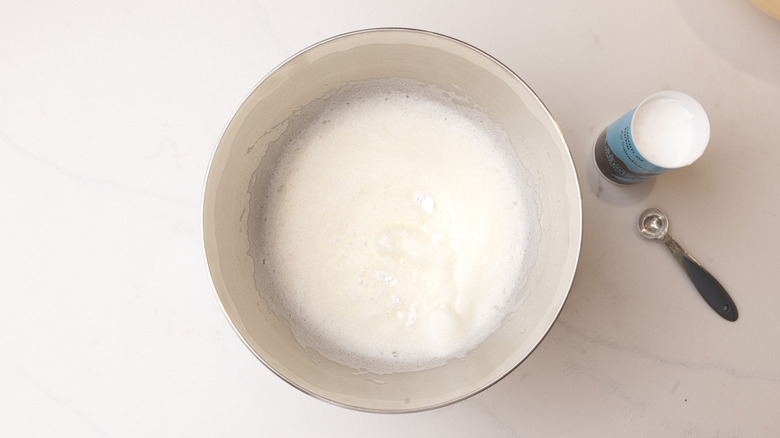 beaten egg whites in a bowl with cream of tartar on top and on the side
