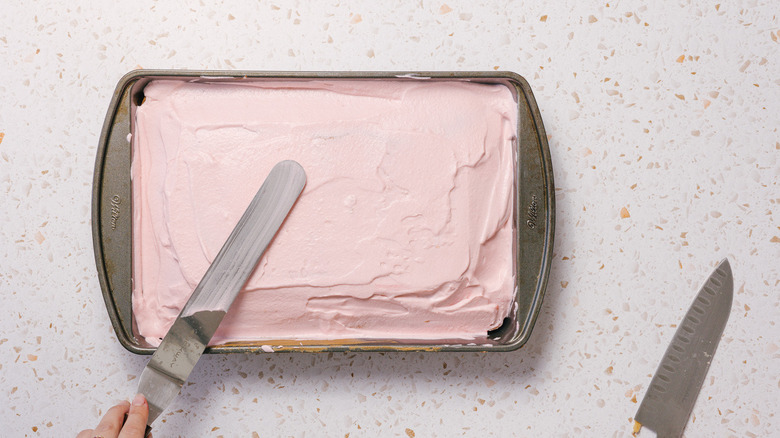 Spreading pink icing on cake