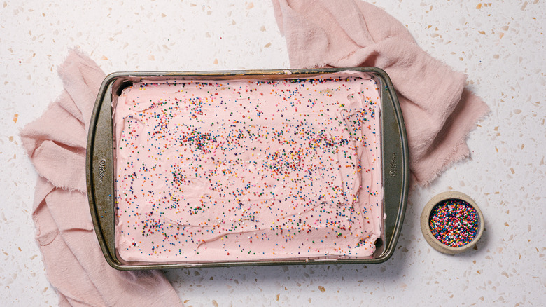 Pan of Mexican pink cake with pink napkins and sprinkles
