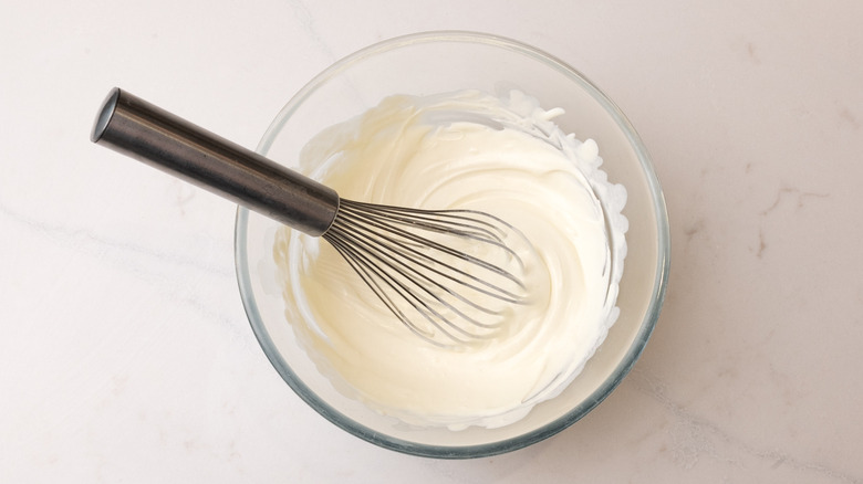 aerial view of whisked cream in a bowl with whisk