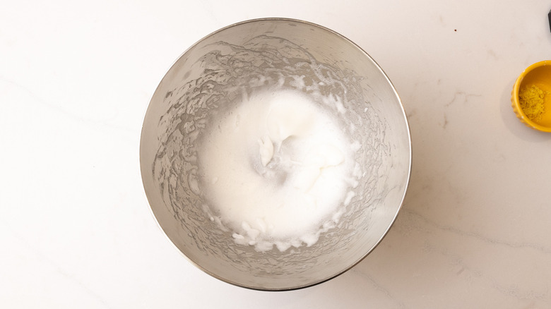 aerial view of whisked egg white in bowl on marble surface