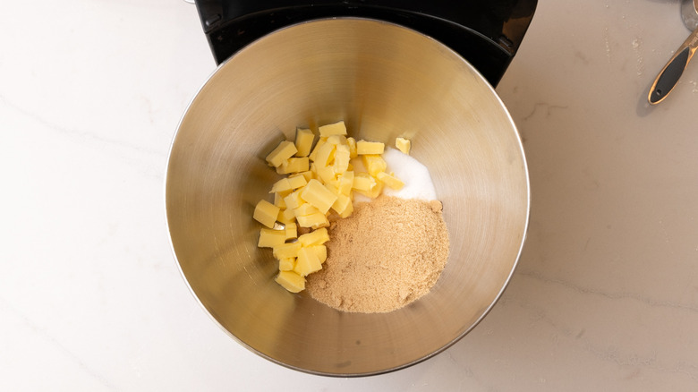 aerial view of brown sugar, granulated sugar, and chopped up butter in a stand mixer bowl
