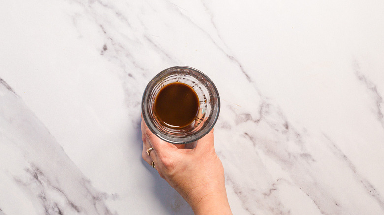 Holding glass with brown coffee mixture