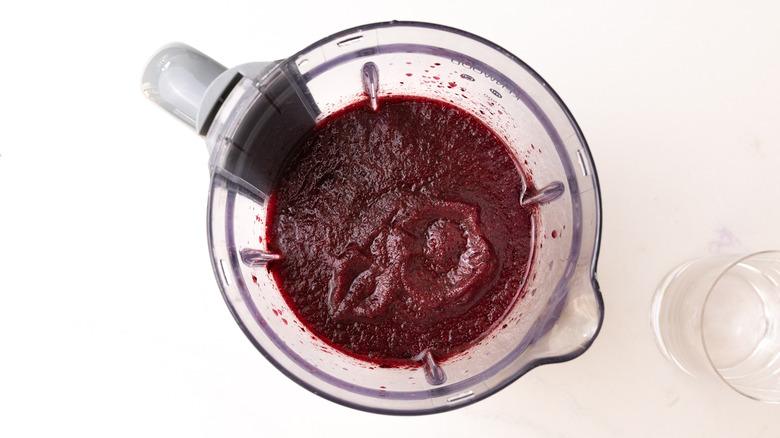 aerial view of blended frozen mojito in processor next to empty cup