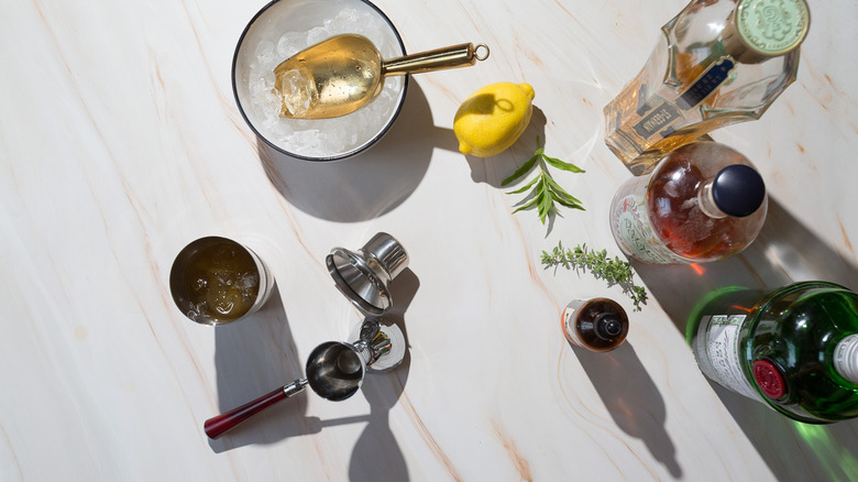 Shaker with ingredients next to bottles