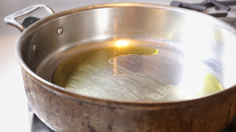 high-walled stainless steel pan with olive oil in it