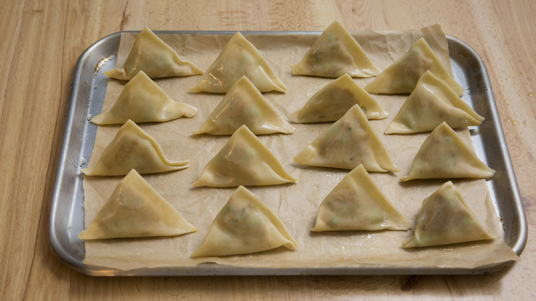 unbaked samosas on baking sheet