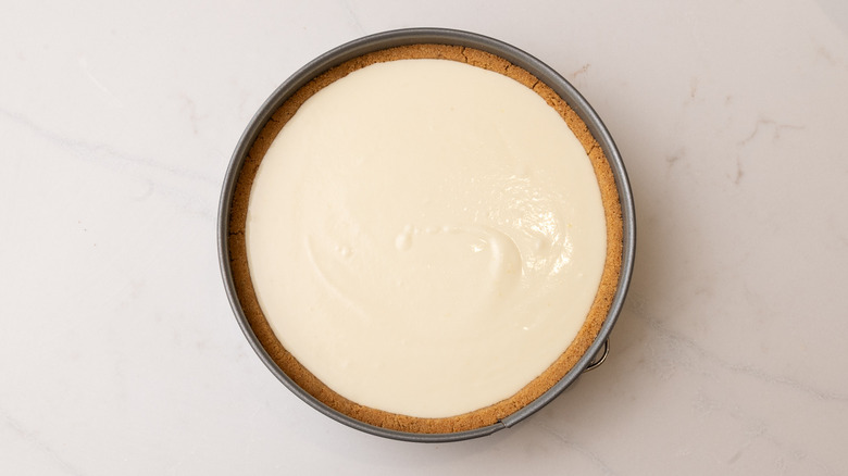 aerial view of pie crust filled with custard filling in cake pan