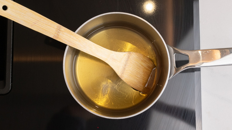 honey elderflower syrup simmering in saucepan with spatula inside