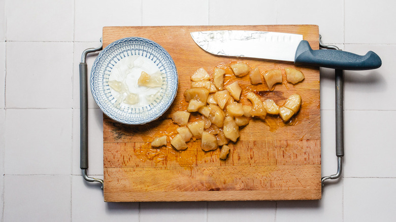 Cut apple slices on a cutting board with knife and small plate