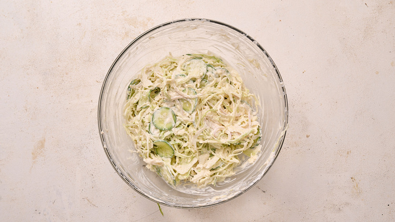 mixing cabbage into bowl with raita