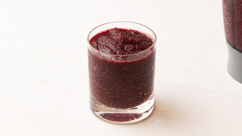 frozen blueberry mojito in glass next to filled blender