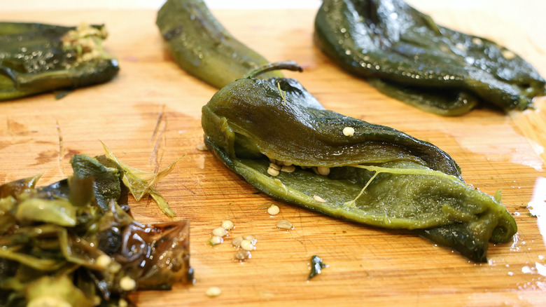 peeled and seed poblano peppers on a wood cutting board