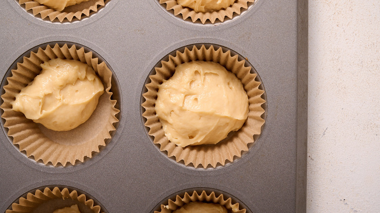 scooping muffin batter into tin