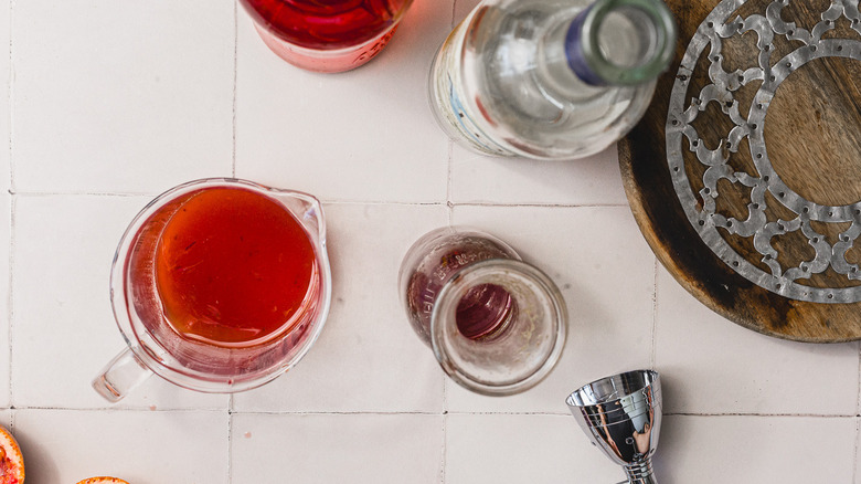 Cocktail in mixing glass next to bottles