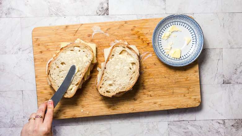 Spreading butter on two sandwiches