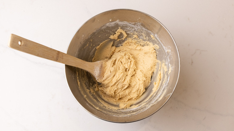 mixing bowl containing raw cookie dough with spatula inside