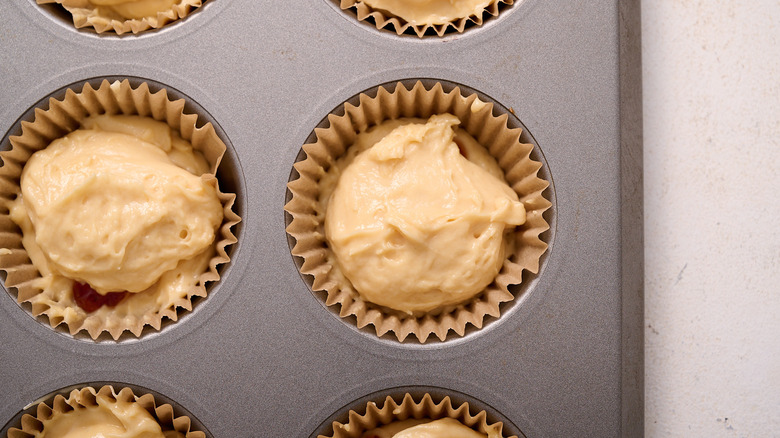 filling muffin tin with muffin batter