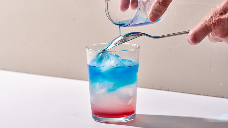 pouring blue mixture into drink