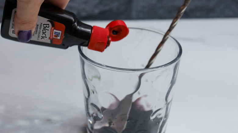 black food coloring being dropped into glass of vodka