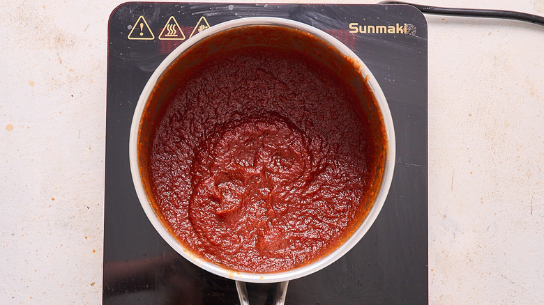 barbecue sauce thickened in a saucepan over induction cooktop