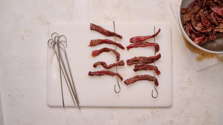 putting beef jerky slices on skewers