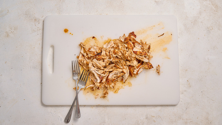 shredding chicken on a cutting board