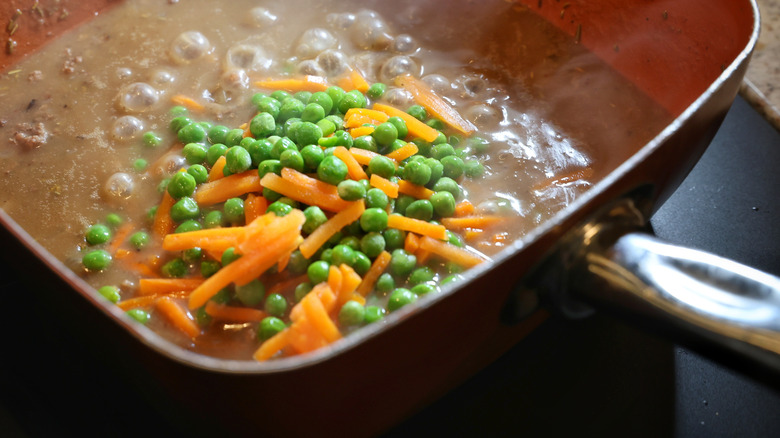 peas and carrots floating in pan of gravy