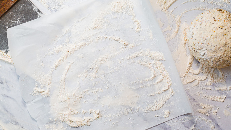 Parchment with flour alongside bench scraper