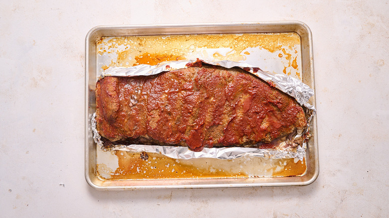 aerial view of baked ribs on a sheet of boil over a saucy baking sheet