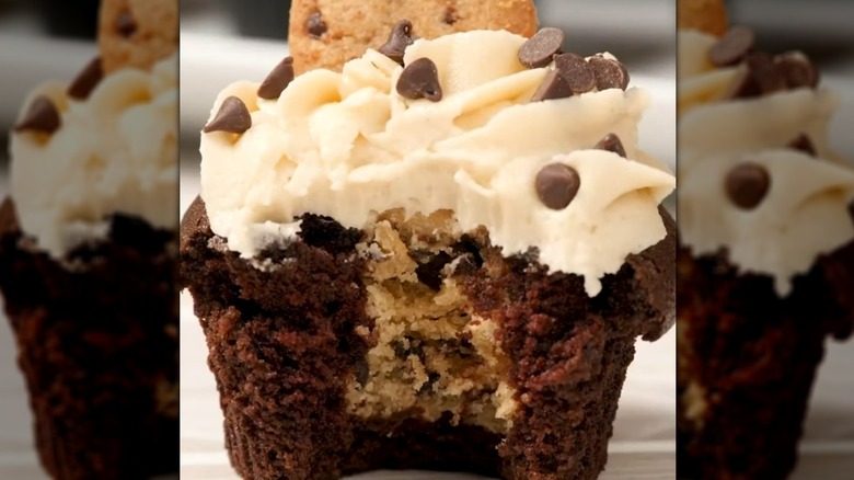 Bitten cookie dough-stuffed chocolate cupcake with vanilla frosting