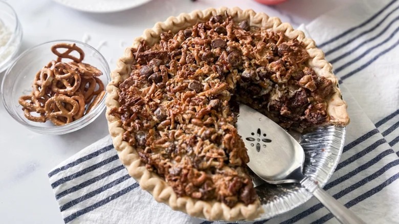 Trash pie with slice removed next to a bowl of pretzels