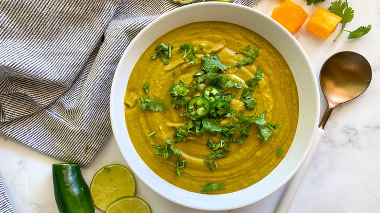 Bowl of butternut squash soup topped with fresh cilantro and jalapeño slices