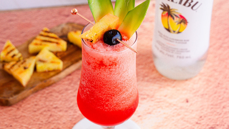 Frozen bahama mama cocktail garnished with a cherry and pineapple leaves