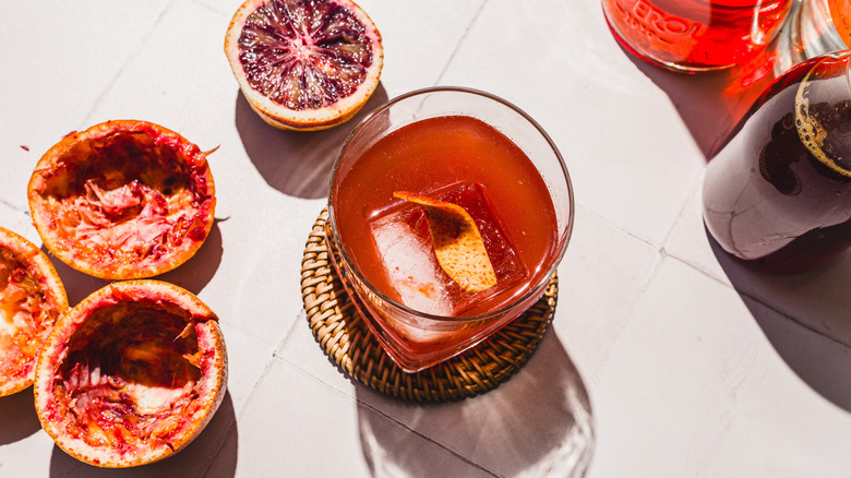 Overhead view of glass with blood orange screwdriver cocktail alongside empty blood orange peels and bottles