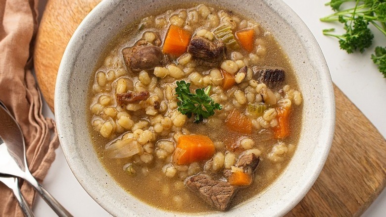 Bowl of beef and barley soup with curly parsley garnish