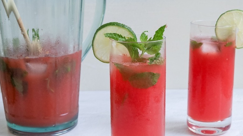 Watermelon mojito cocktail in a pitcher and glasses with lime and mint garnishes