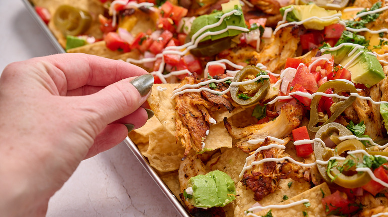 hand pulling a nacho from the pile