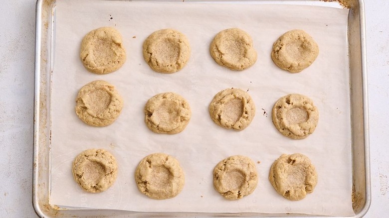 Baked cookies with shallow wells on baking sheet